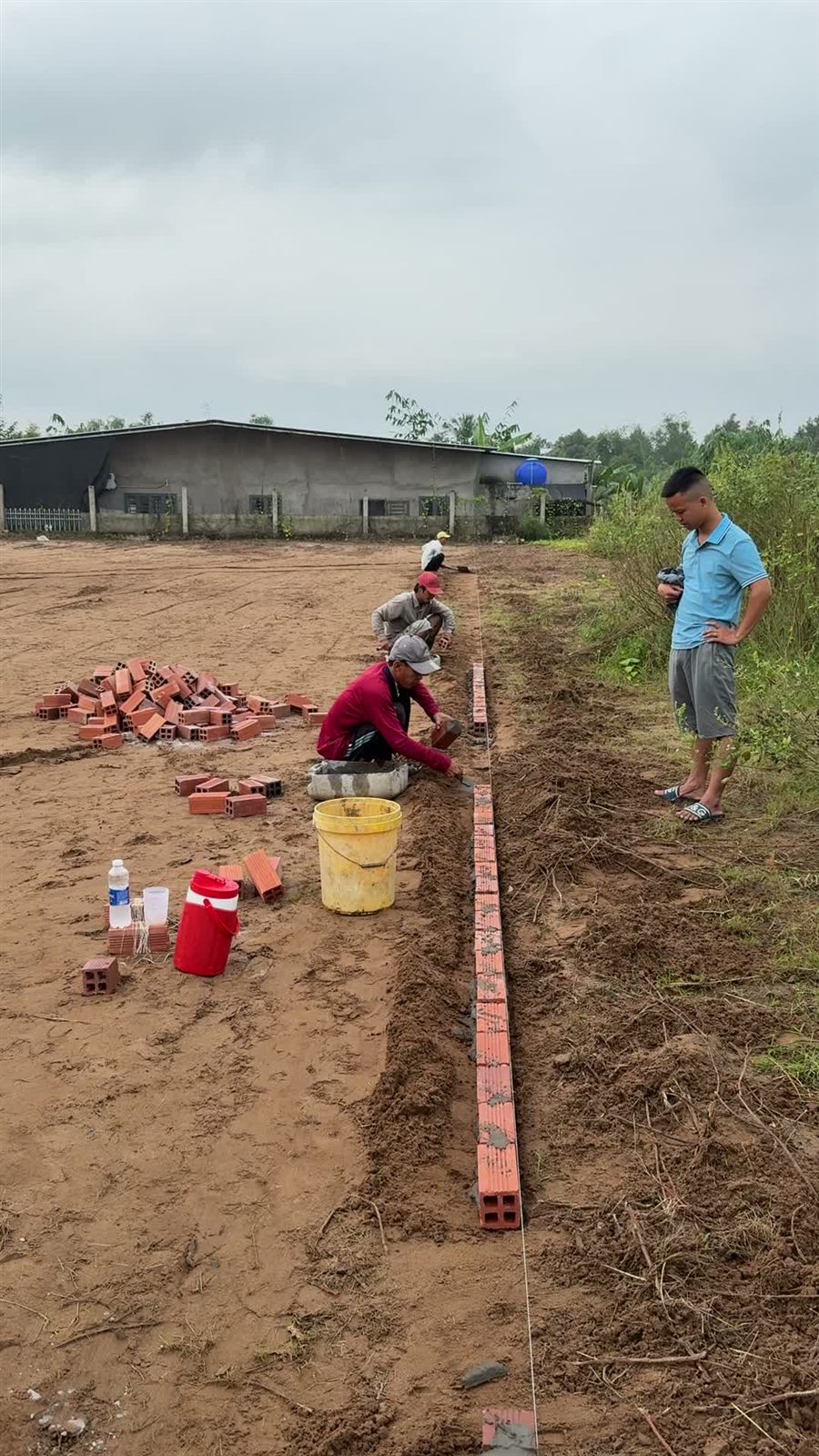 Đội thi công xây bó vỉa gạch quanh lòng sân cỏ nhân tạo Phú Phụng, Vĩnh Long