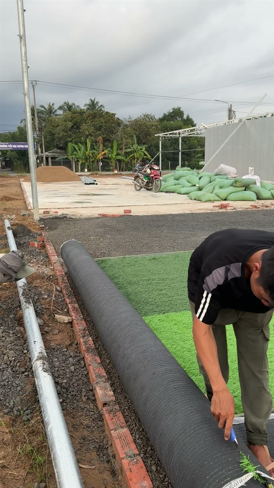 Nền đá mạt lu lèn phẳng và bó vỉa gạch đỏ trước khi trải cỏ tại sân Phú Phụng